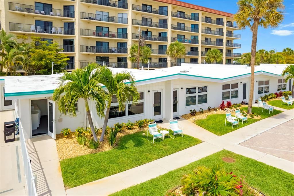 A low-rise white building with a flat roof sits in front of a tall apartment complex — 6334 MIDNIGHT PASS ROAD UNIT 41, SARASOTA, FL