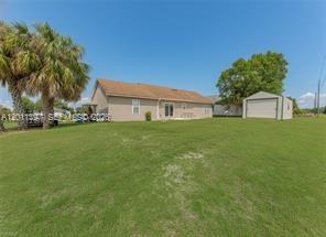 The exterior of a beige house with a detached garage sits on a large lawn — 1500 Jay Ter, La Belle FL 33935, LA BELLE, FL