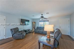 A living room features gray furniture, light wood-look flooring, and a ceiling fan — 1500 Jay Ter, La Belle FL 33935, LA BELLE, FL