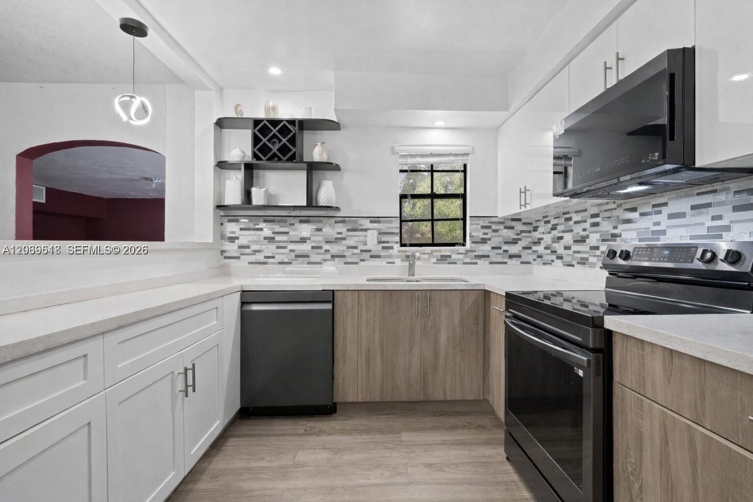A modern kitchen features white upper cabinets, wood-look lower cabinets, and a mosaic tile backsplash — 65 NW 118th St, Miami FL 33168, MIAMI, FL