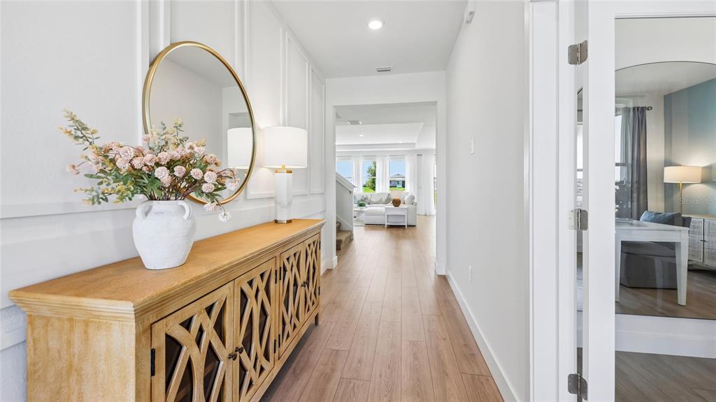 A hallway features a wooden console table, a round mirror, and a view into a living area — 1627 NW 128TH TERRACE, NEWBERRY, FL