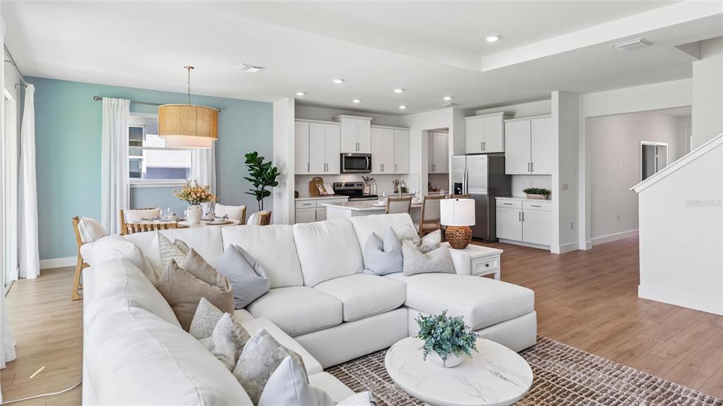 An open-concept living room features a white sectional sofa, dining area, and modern kitchen — 1627 NW 128TH TERRACE, NEWBERRY, FL