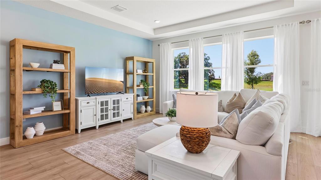 A living room features a white media console, wooden bookshelves, and a sectional sofa — 1627 NW 128TH TERRACE, NEWBERRY, FL