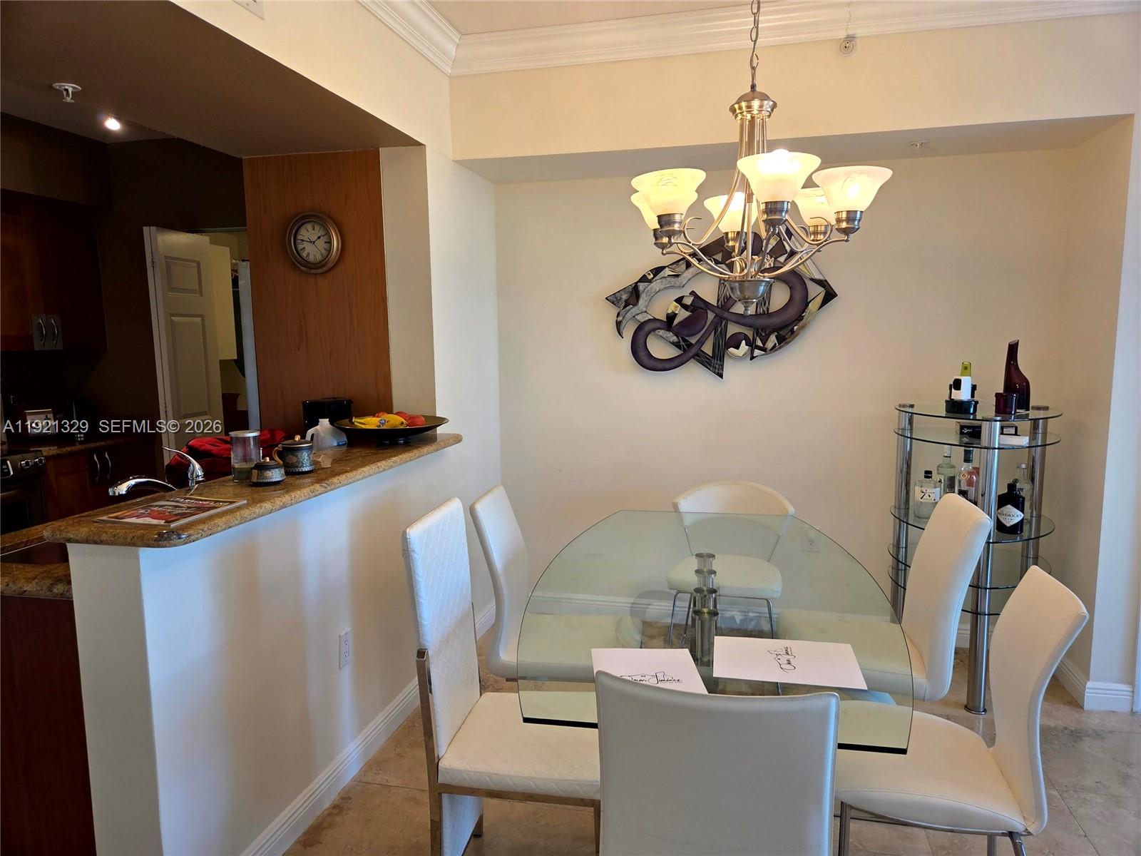 A dining area features a glass table, white chairs, a chandelier, and a bar cart — 1755 E Hallandale Beach Blvd # 305E, Hallandale Beach FL 33009, HALLANDALE BEACH, FL