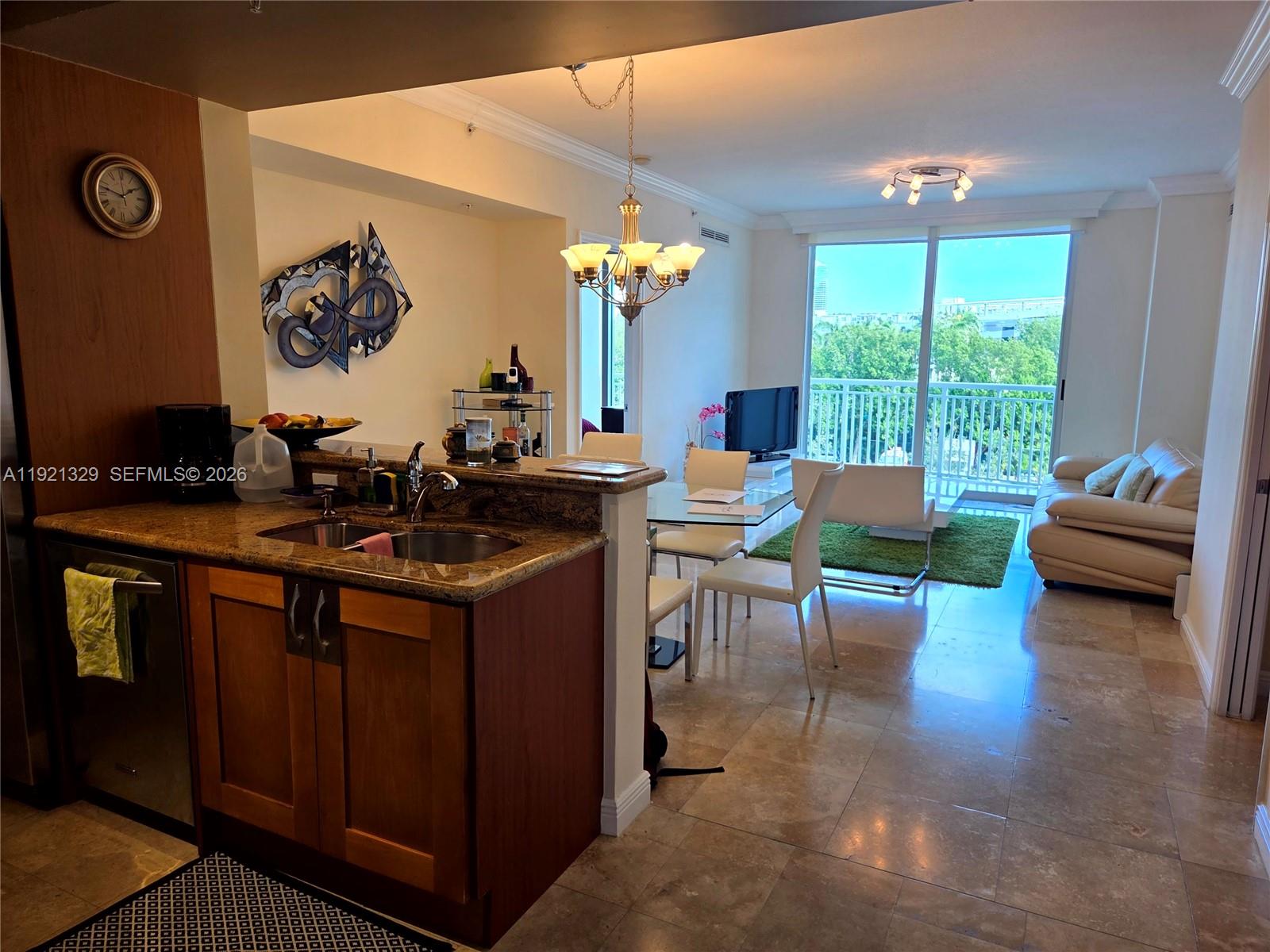 A kitchen with granite countertops overlooks a dining area and living room with balcony access — 1755 E Hallandale Beach Blvd # 305E, Hallandale Beach FL 33009, HALLANDALE BEACH, FL