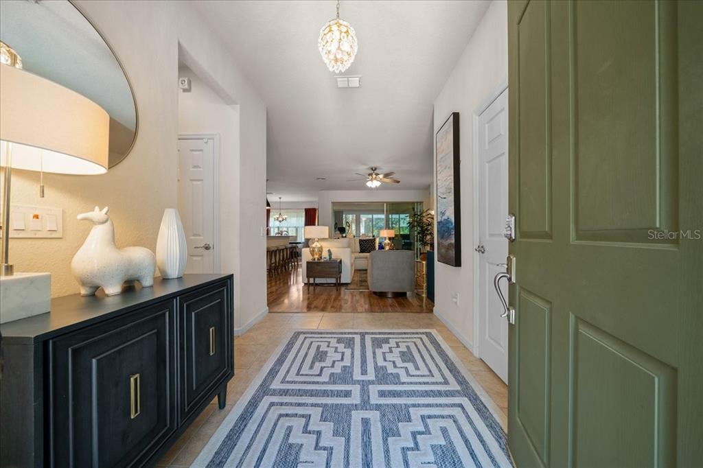 An entryway with a patterned rug, a dark console table, and a view into the living room — 9841 SW 75TH STREET ROAD, OCALA, FL