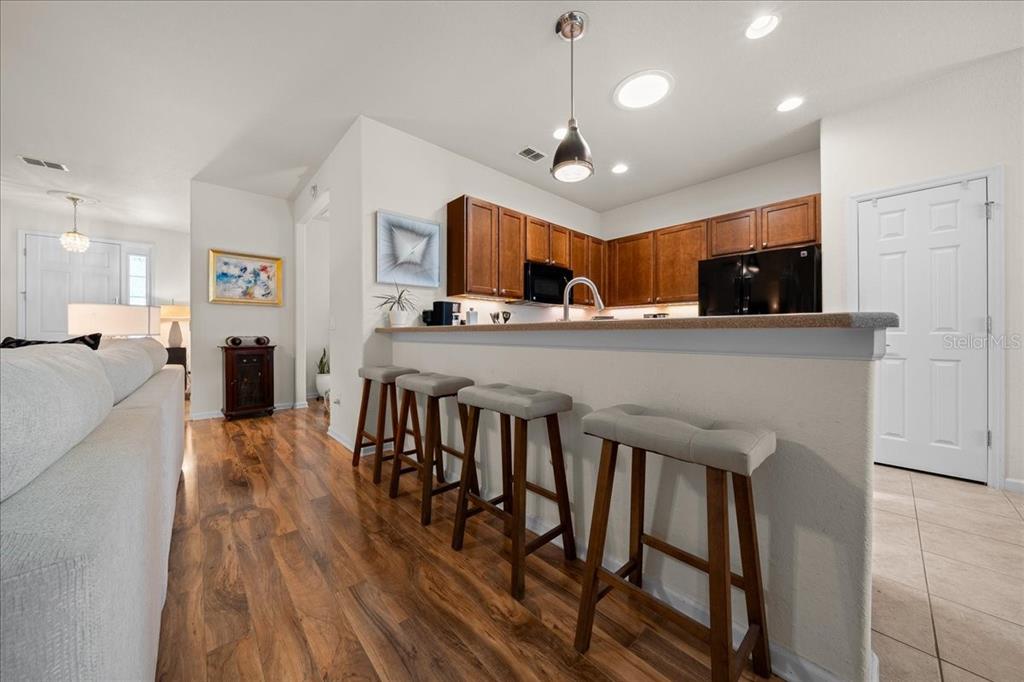 A kitchen with wood cabinets and a breakfast bar featuring four stools faces a living area — 9841 SW 75TH STREET ROAD, OCALA, FL