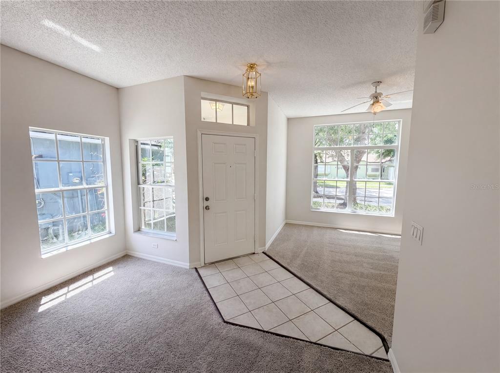 An entryway with a tiled floor transition, carpeted living area, and multiple windows — 6202 LIGHTNER DRIVE, ORLANDO, FL