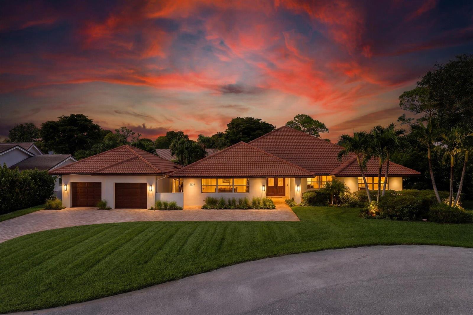 A single-story house with a tiled roof and two-car garage at sunset — 4535 Oak Tree Court, Delray Beach FL 33445, DELRAY BEACH, FL