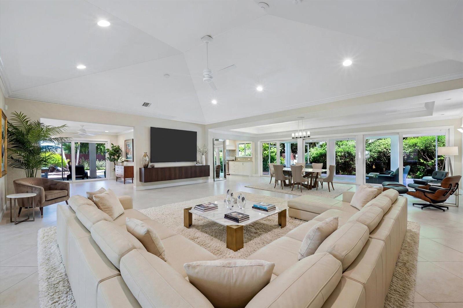 A spacious open-concept living room features a large sectional sofa, vaulted ceilings, and glass doors — 4535 Oak Tree Court, Delray Beach FL 33445, DELRAY BEACH, FL
