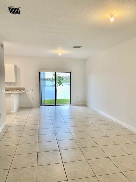 An open-concept living area with tile flooring and sliding glass doors overlooking a lake — 20626 NE 5th Pl # 20626, Miami FL 33179, MIAMI, FL