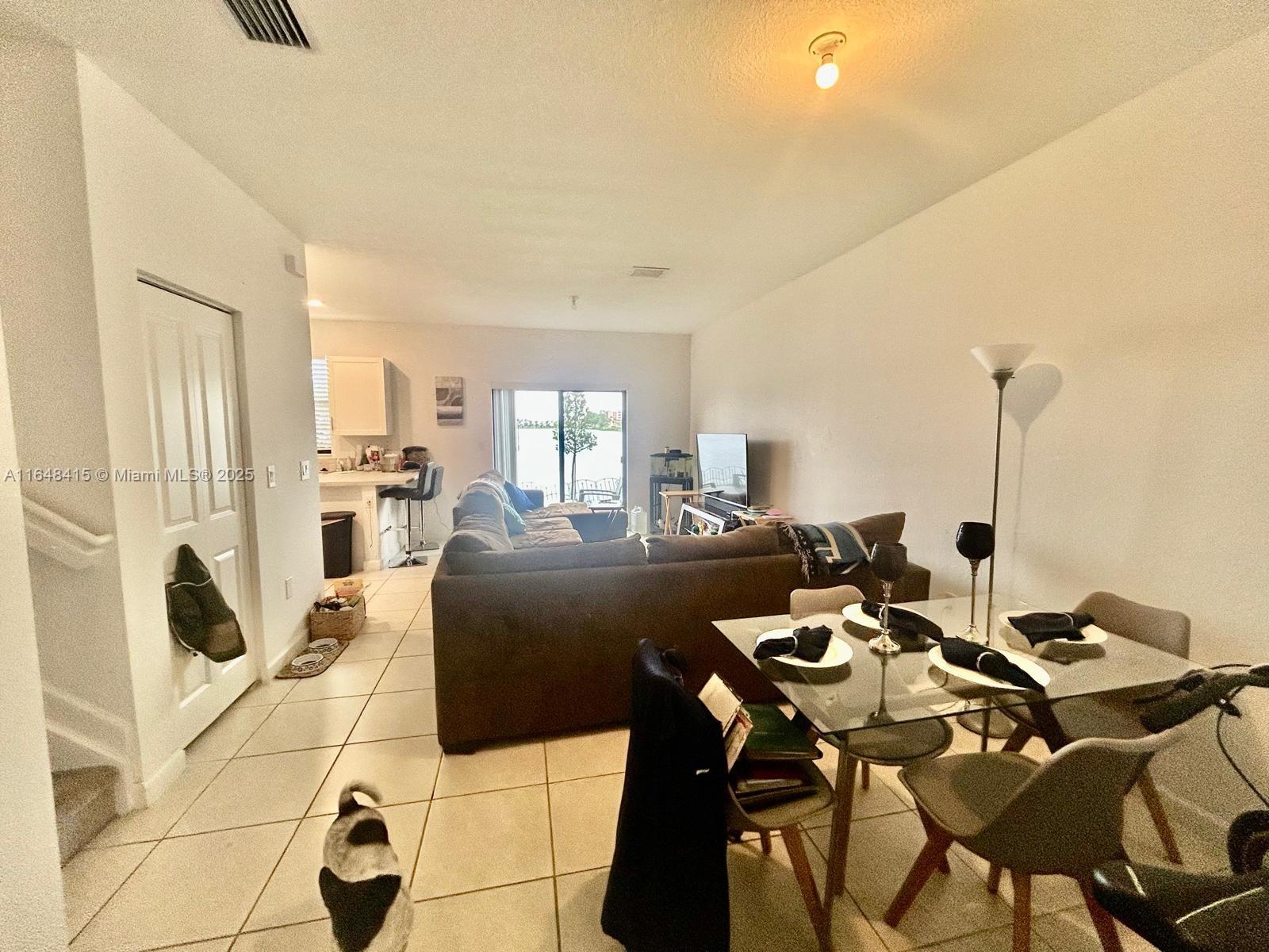 This open-concept living and dining area features tile flooring, a glass dining table, and a sofa — 20626 NE 5th Pl # 20626, Miami FL 33179, MIAMI, FL