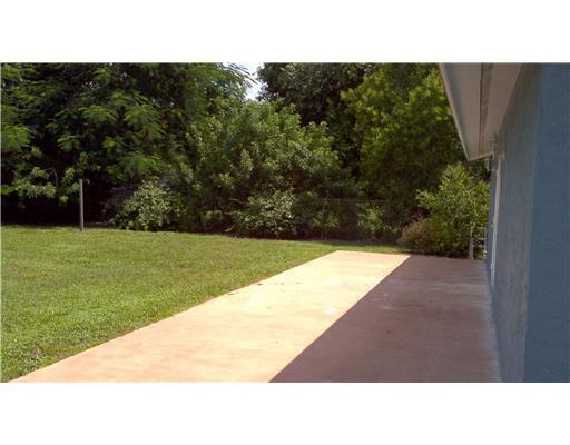 A concrete patio extends from the side of a house next to a grassy yard — 6315 Bischoff Road, West Palm Beach FL 33413, WEST PALM BEACH, FL