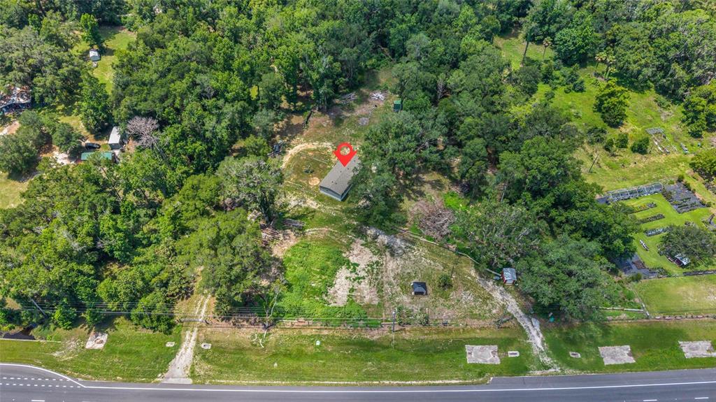 An aerial view shows a house with a red location pin situated on a wooded lot — 24050 CORTEZ BOULEVARD, BROOKSVILLE, FL