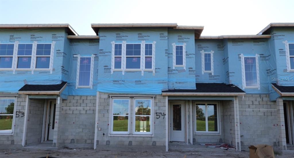 An exterior view of a row of unfinished townhomes with blue house wrap and concrete blocks — 3534 CASPIAN CHERVIL STREET, WESLEY CHAPEL, FL