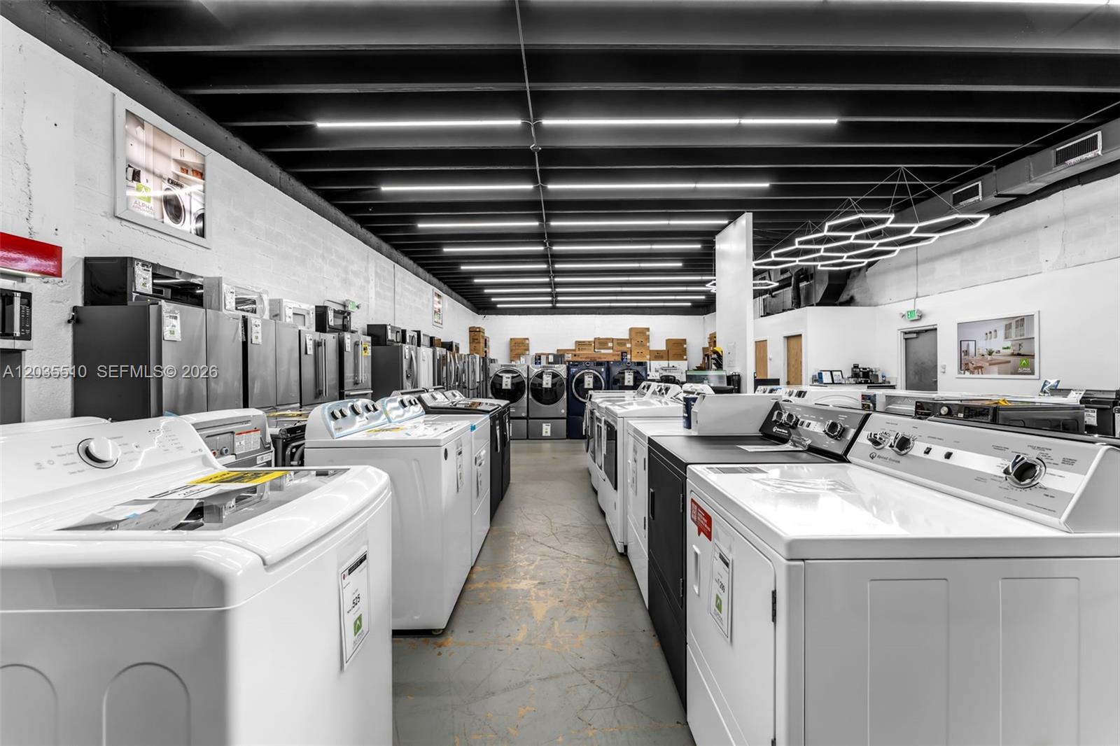 A retail showroom displays rows of white and black laundry appliances on a concrete floor — 12134 SW 114 Place, Miami FL 33176, MIAMI, FL