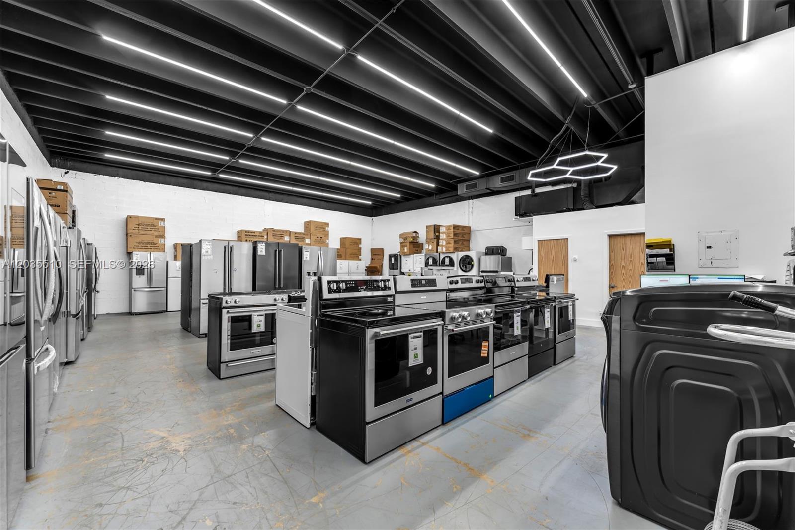 This retail showroom displays various stainless steel kitchen appliances under a black industrial ceiling — 12134 SW 114 Place, Miami FL 33176, MIAMI, FL