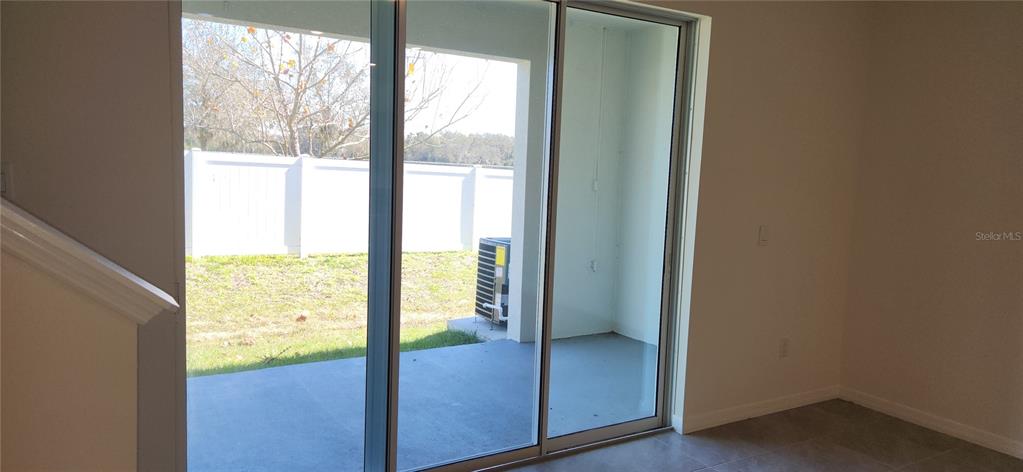 A room with tile flooring looks out through sliding glass doors onto a covered patio — 9241 ROCK HARBOUR WAY, TAMPA, FL