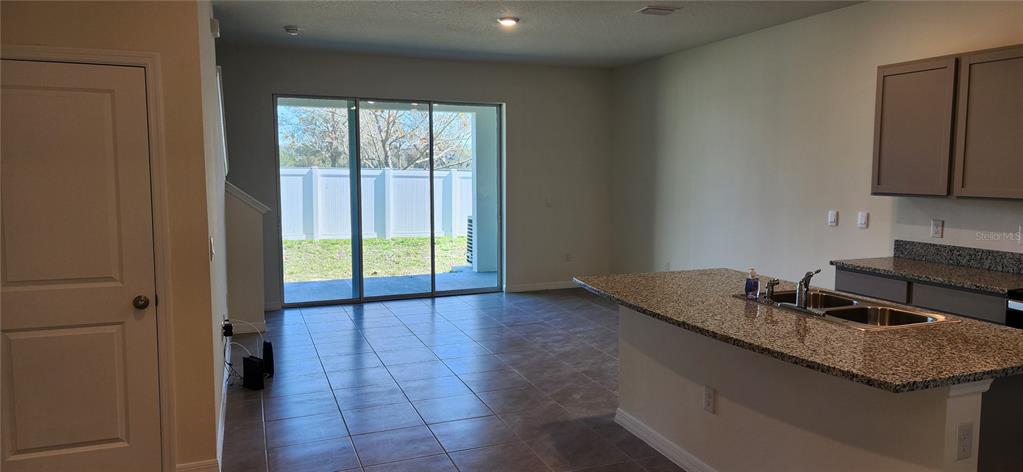 A kitchen with granite countertops and an island overlooks a living area with sliding doors — 9241 ROCK HARBOUR WAY, TAMPA, FL