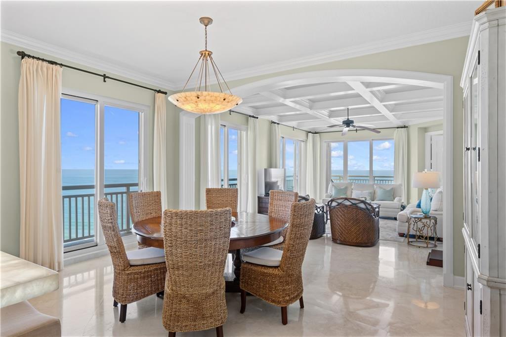 A dining area with a round wooden table and wicker chairs opens into a living room — HUTCHINSON ISLAND, FL