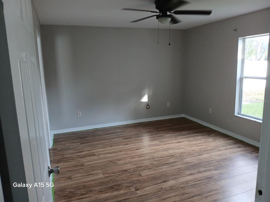 An empty bedroom features gray walls, wood-look flooring, a ceiling fan, and a window — 7500 LULLWATER AVENUE, SPRING HILL, FL