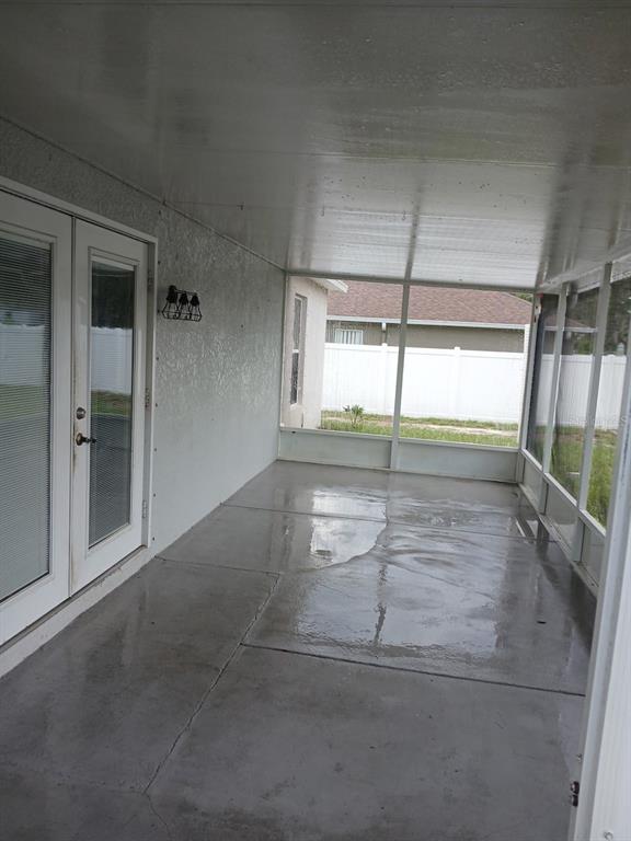 A covered concrete patio with screen walls and a white door leading inside — 7500 LULLWATER AVENUE, SPRING HILL, FL