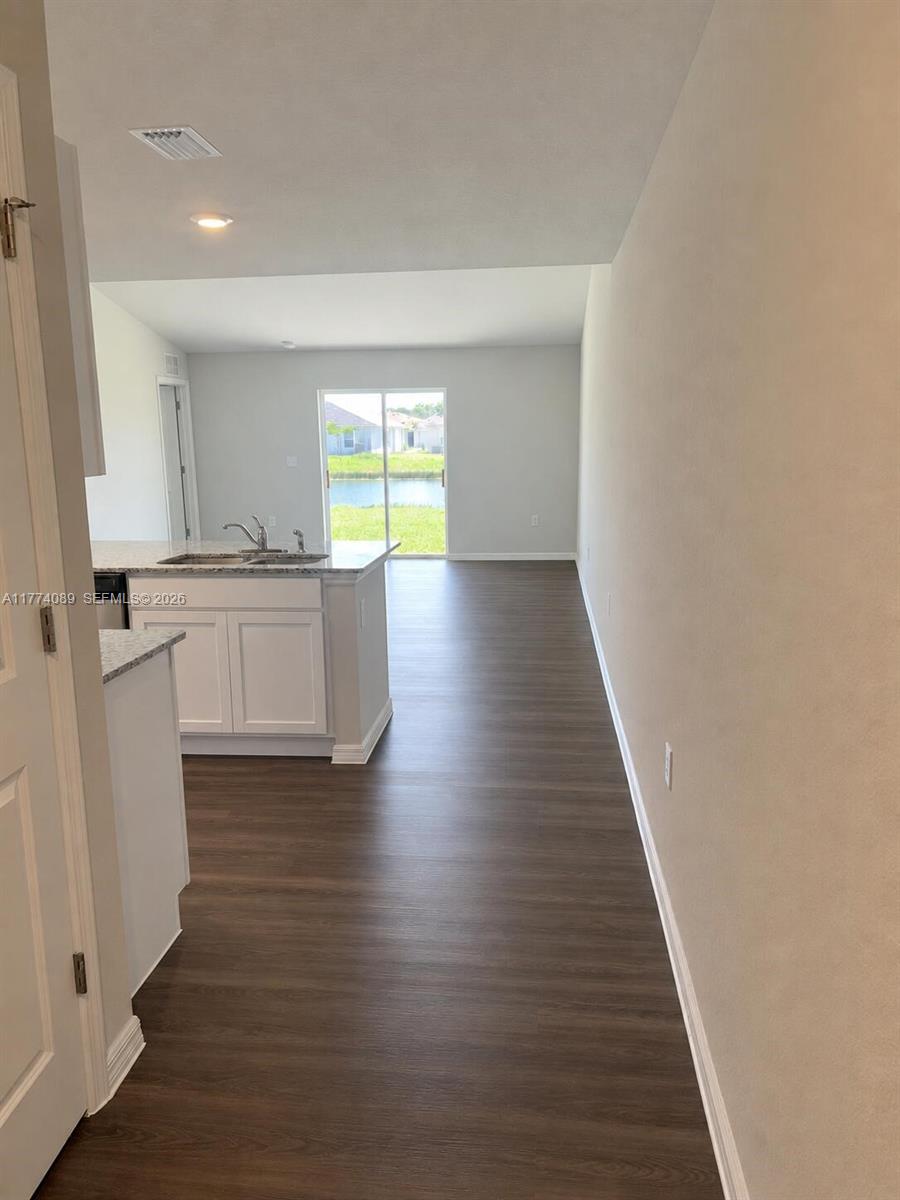 A kitchen with white cabinets and a granite island overlooks a living area with water views — 9084 Aegean Cir, Lehigh Acres FL 33936, LEHIGH ACRES, FL