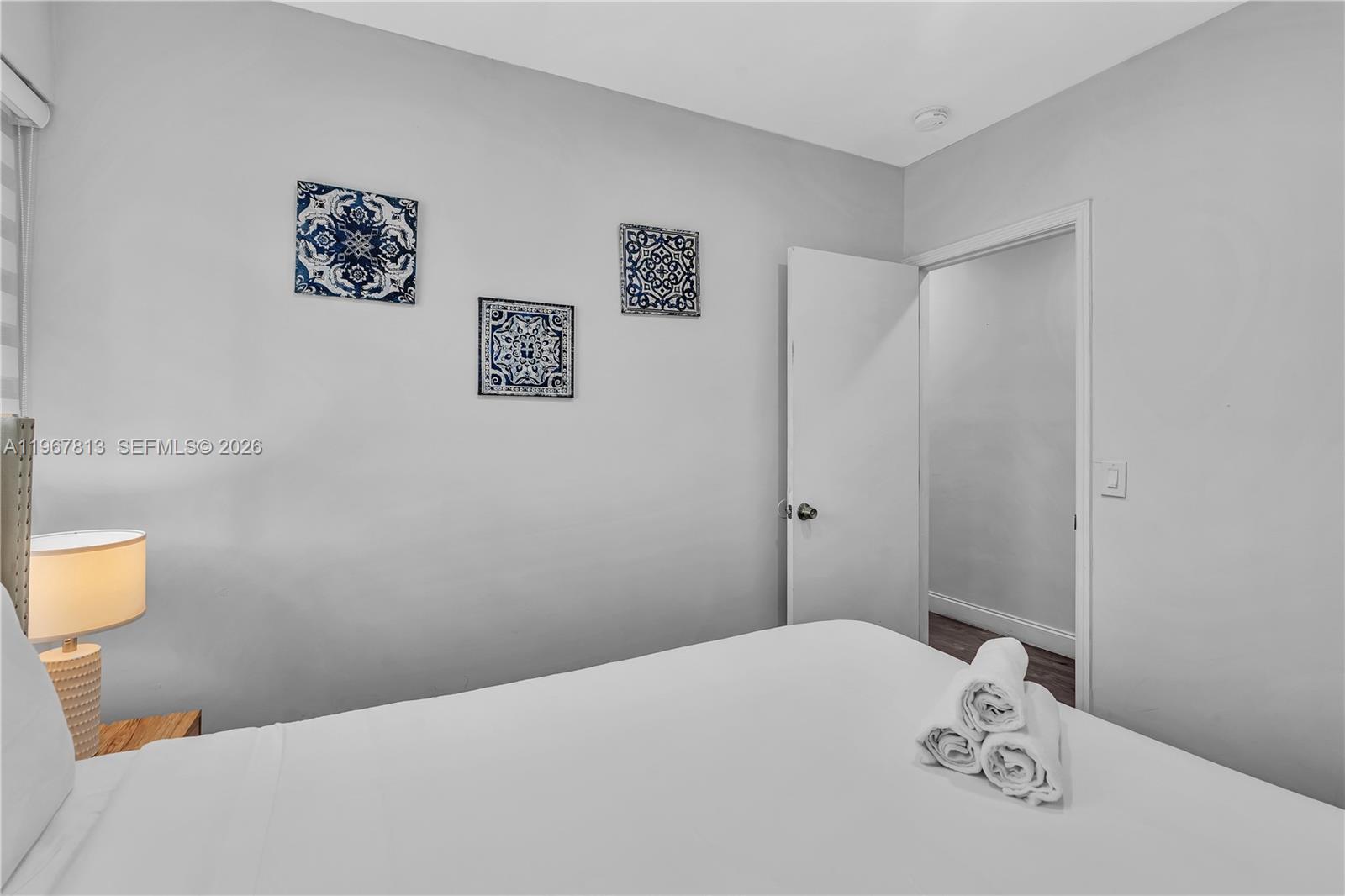 A bedroom features a bed with white linens, a bedside lamp, and three decorative wall tiles — 10002 E Bay Harbor Dr # 6, Bay Harbor Islands FL 33154, BAY HARBOR ISLANDS, FL