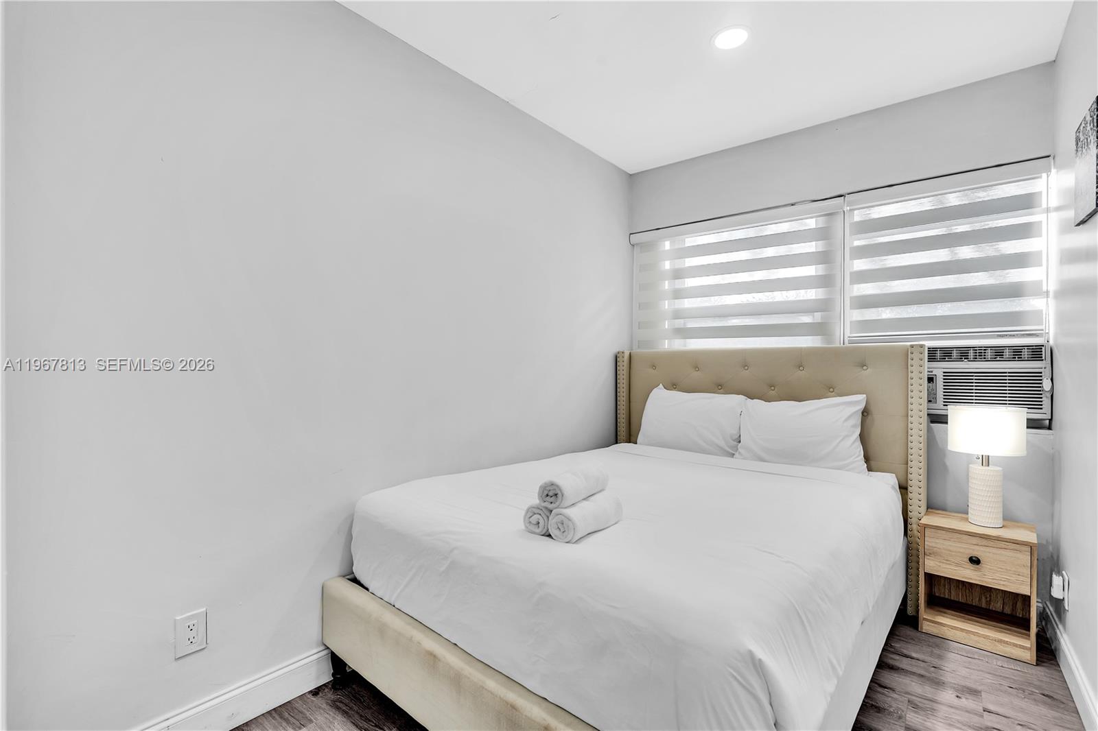 A bedroom features a tufted headboard, a bed with white linens, and a window unit — 10002 E Bay Harbor Dr # 6, Bay Harbor Islands FL 33154, BAY HARBOR ISLANDS, FL