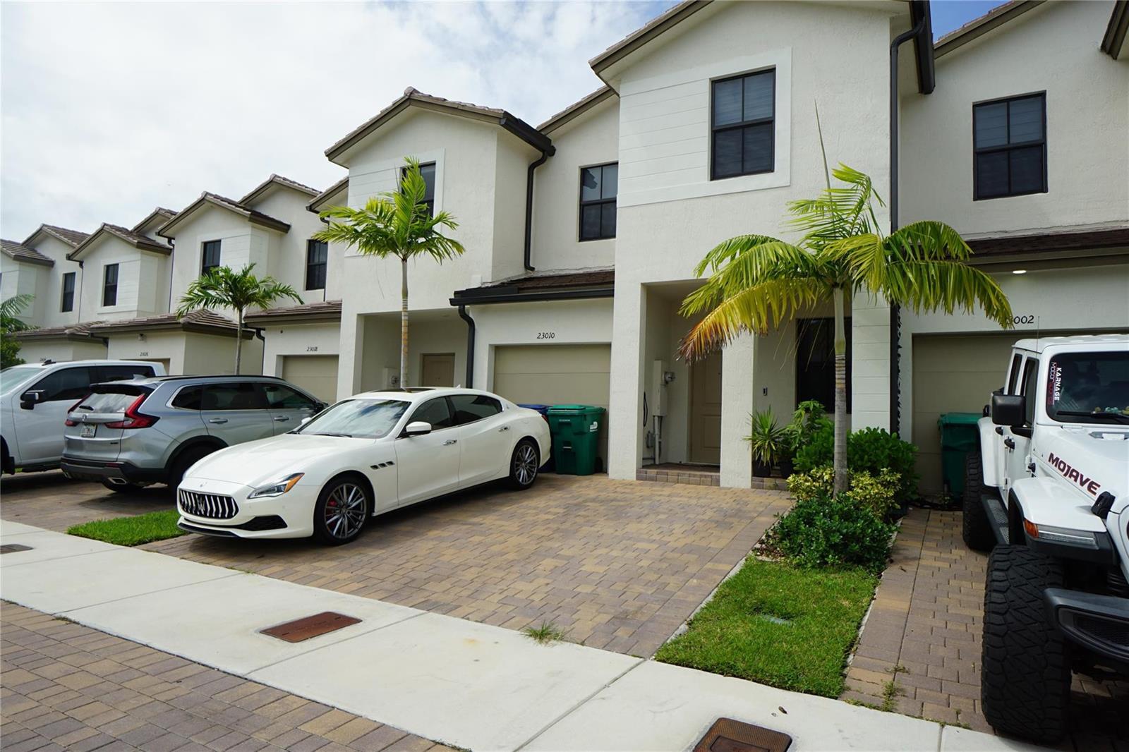 A row of two-story townhomes with paved driveways, parked cars, and palm trees — 23010 SW 128th Place # 23010, Miami FL 33170, MIAMI, FL