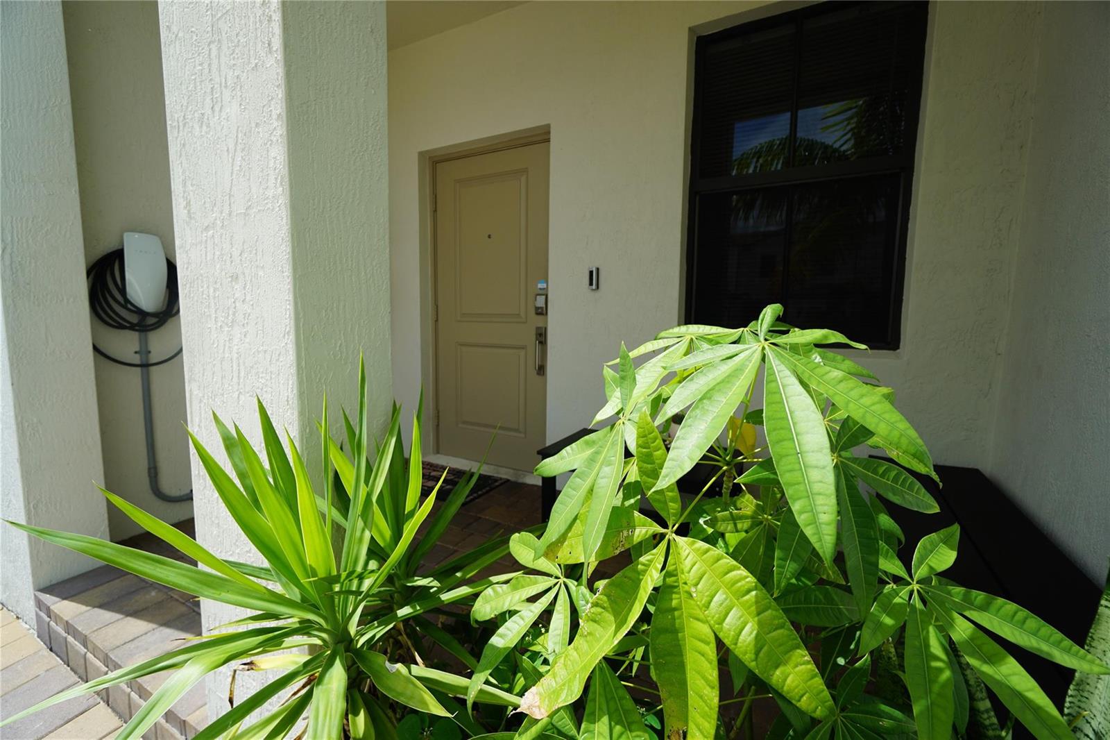 A front porch features a beige door, a window, and a wall-mounted electric vehicle charger — 23010 SW 128th Place # 23010, Miami FL 33170, MIAMI, FL