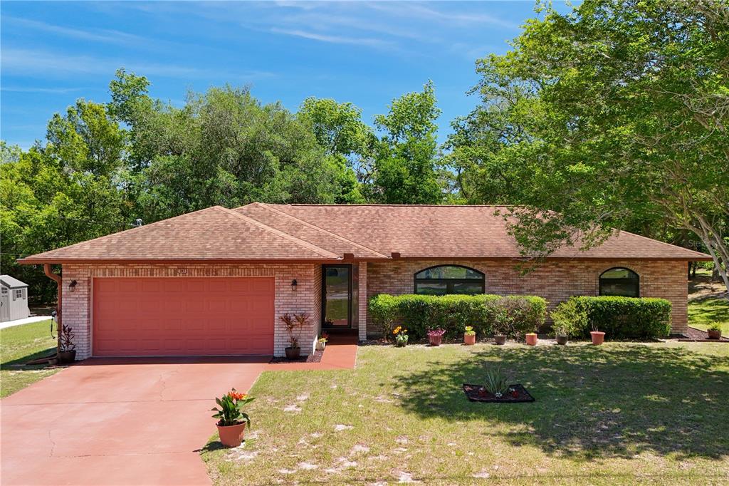 A single-story brick house with a red garage door, arched windows, and a paved driveway — 283 CHESTNUT AVENUE, ORANGE CITY, FL