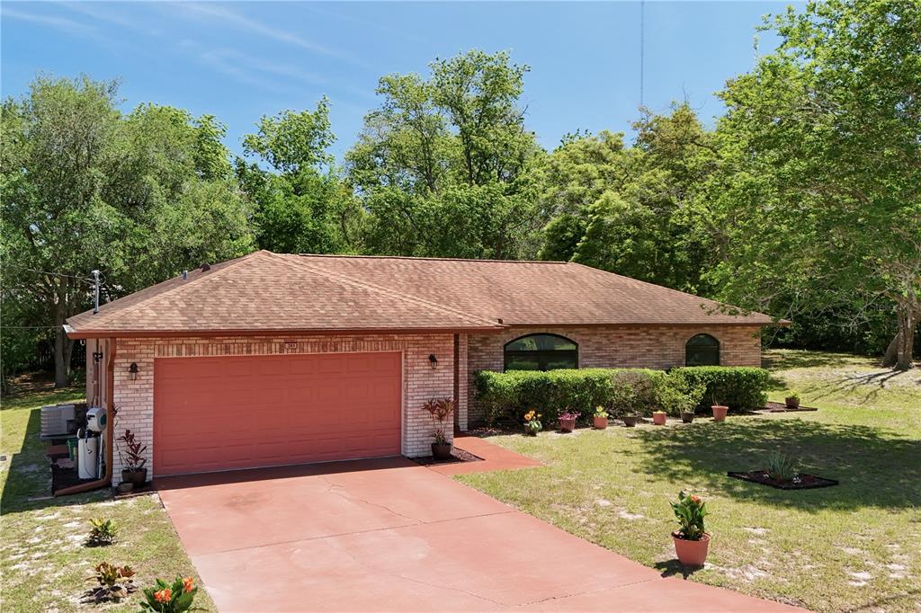 A single-story brick house with a red garage door and a matching red concrete driveway — 283 CHESTNUT AVENUE, ORANGE CITY, FL