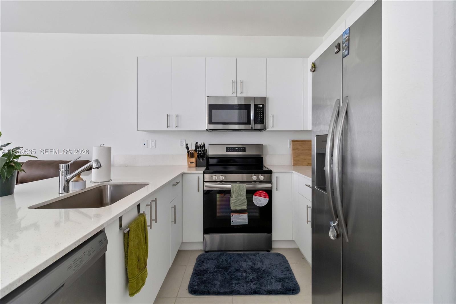 A modern kitchen features white cabinets, stainless steel appliances, and a white quartz countertop — 760 SE 13th Ct, Homestead FL 33034, HOMESTEAD, FL