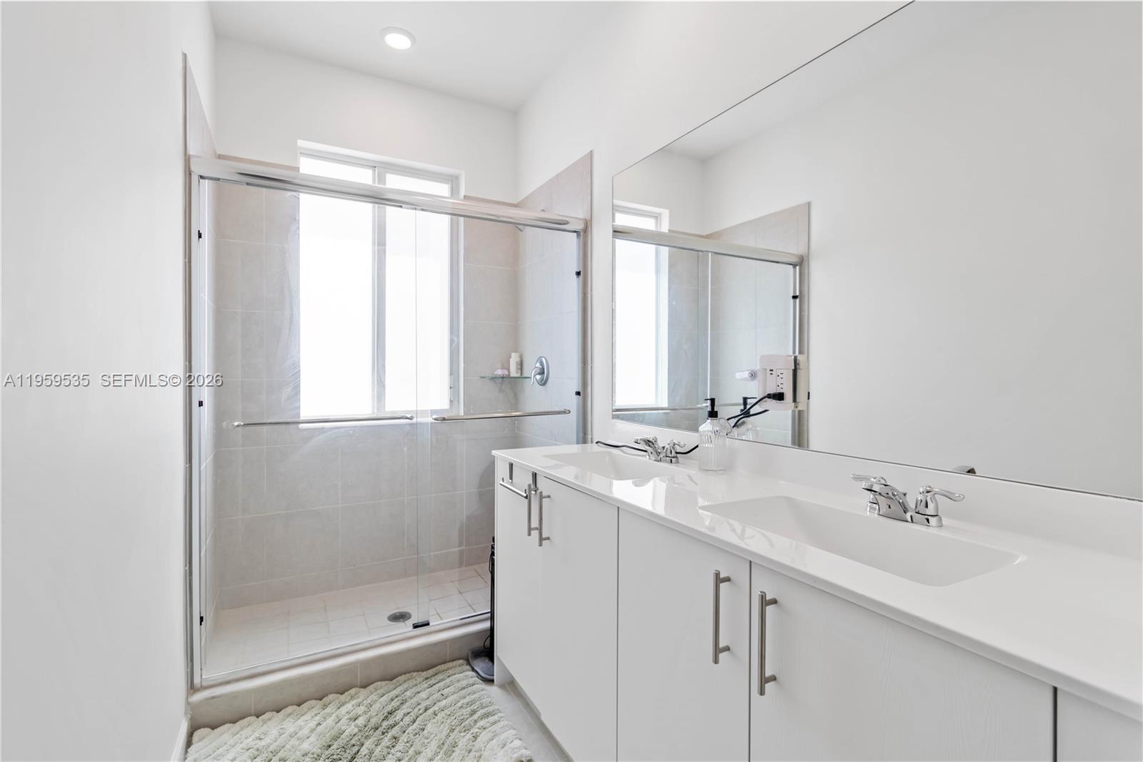 A modern bathroom features a double vanity with white cabinets and a glass-enclosed shower — 760 SE 13th Ct, Homestead FL 33034, HOMESTEAD, FL