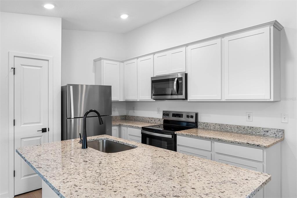 A kitchen features white cabinets, granite countertops, stainless steel appliances, and a central island — 12249 SHAFTON ROAD, SPRING HILL, FL