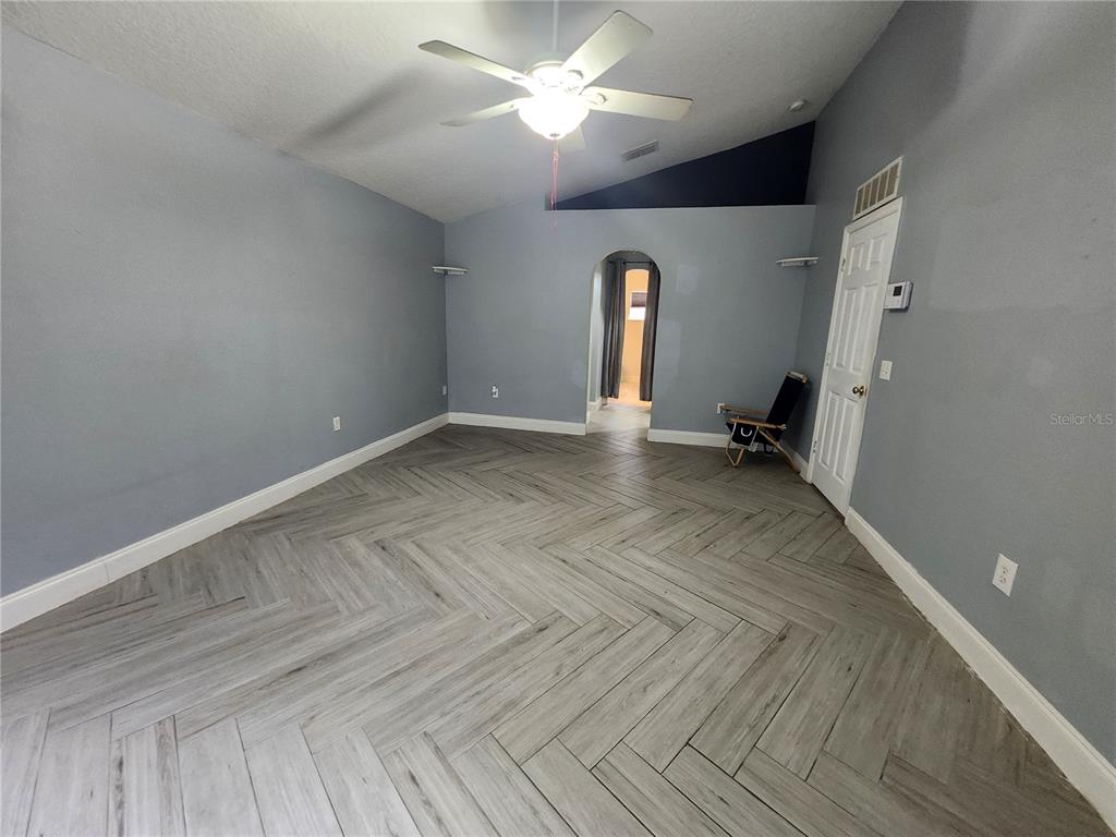 An empty room features gray walls, a vaulted ceiling, and light-colored herringbone-patterned tile flooring — 2200 EL MARRA DRIVE, OCOEE, FL
