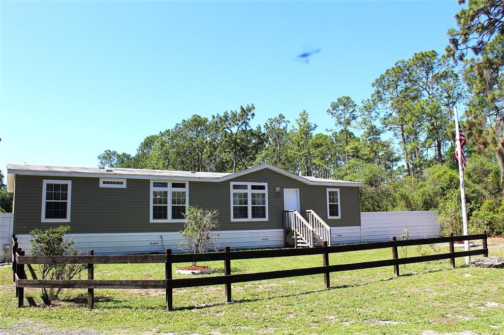 A single-story manufactured home with olive siding sits behind a wooden fence — 175 E SAN JOSE STREET, PALATKA, FL
