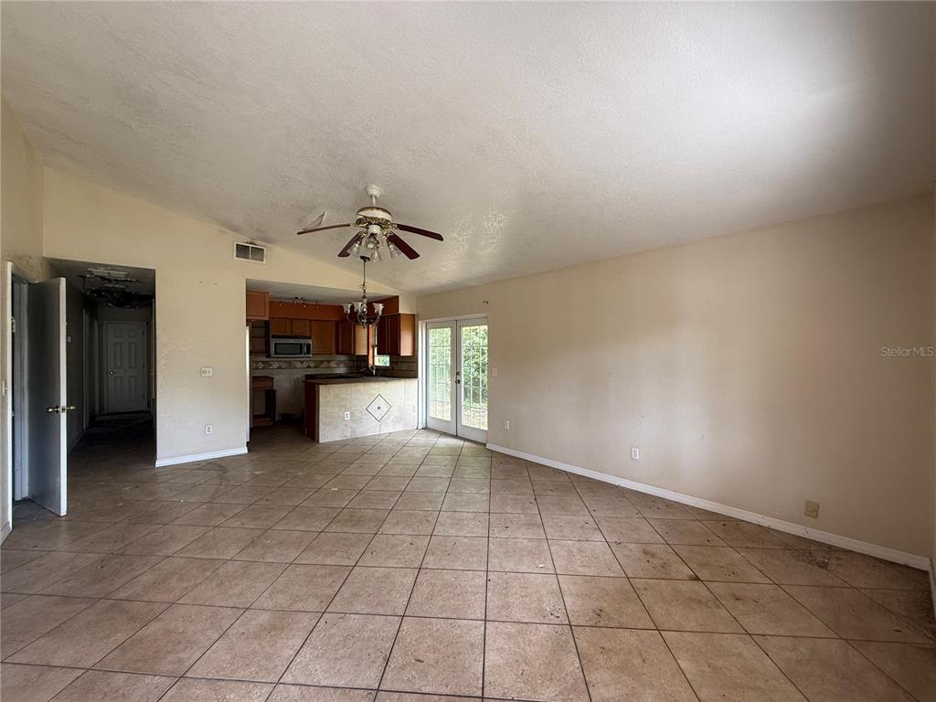 An open-concept living area features diagonal floor tiles, a ceiling fan, and an adjacent kitchen — 5710 JOYCE STREET, ORLANDO, FL