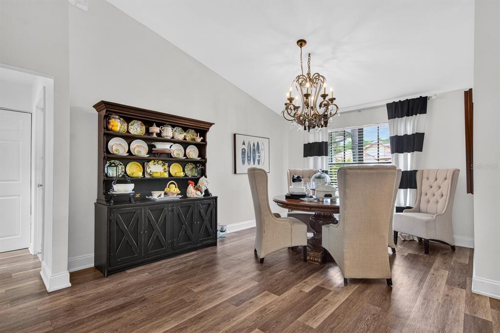 A dining room features a dark wood hutch, a round table with upholstered chairs, and chandelier — 16 CITRUS DRIVE, PALM HARBOR, FL