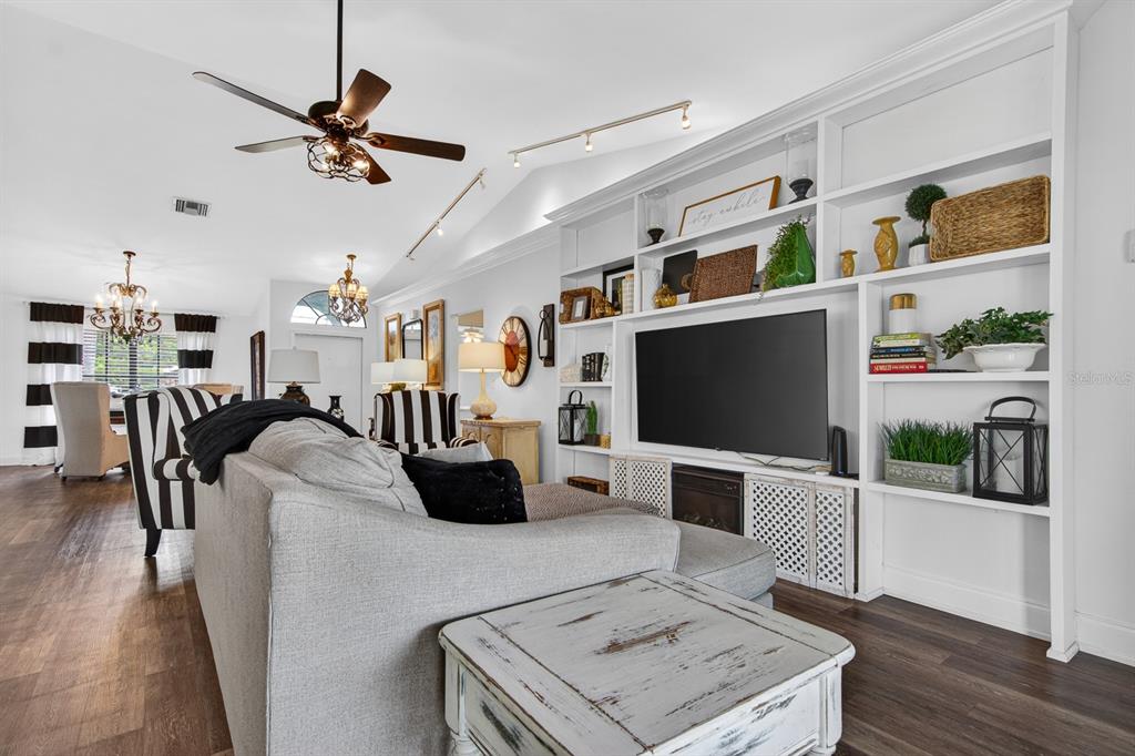 A living room features a large built-in white bookshelf surrounding a wall-mounted television — 16 CITRUS DRIVE, PALM HARBOR, FL