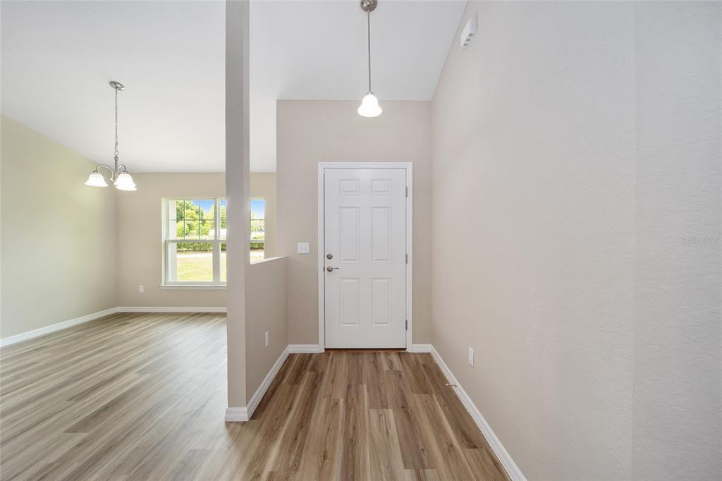 An entryway with wood-look flooring leads to a white front door and an adjacent dining area — 12297 SW 87TH STREET, DUNNELLON, FL