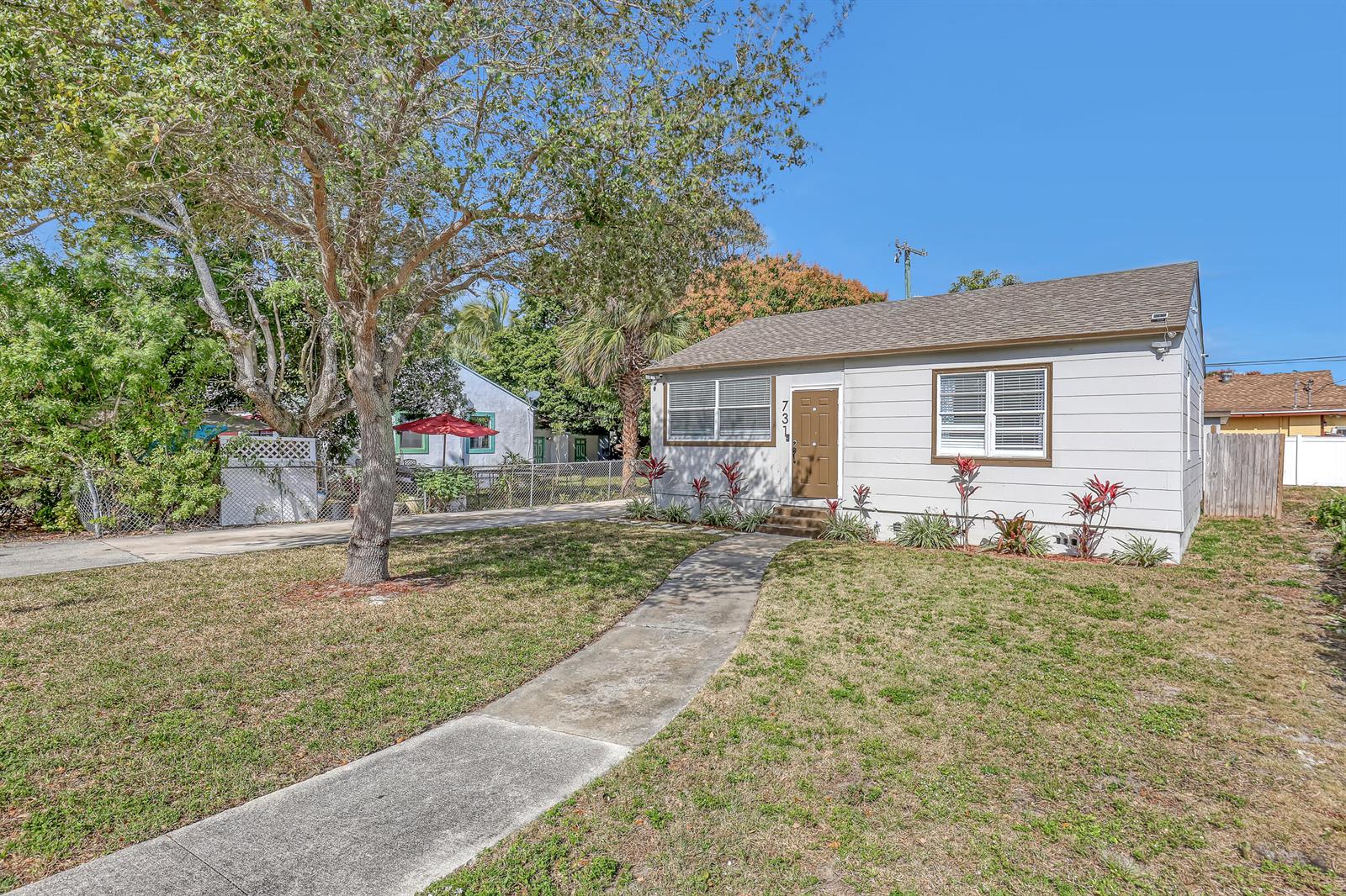 A single-story house with light siding, a brown door, and a concrete walkway in front — 731 50th Street, West Palm Beach FL 33407, WEST PALM BEACH, FL