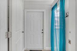 A white interior door stands at the end of a hallway with bright blue curtains — 731 50th Street, West Palm Beach FL 33407, WEST PALM BEACH, FL