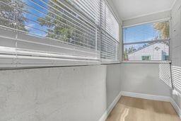 A sunroom with light wood flooring, gray walls, and white horizontal blinds on the windows — 731 50th Street, West Palm Beach FL 33407, WEST PALM BEACH, FL