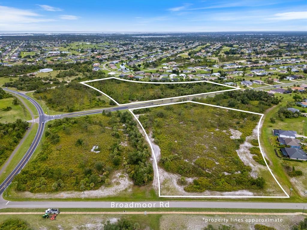 An aerial view shows two vacant, brush-covered lots separated by a road — 151 ROTONDA BOULEVARD N, ROTONDA WEST, FL