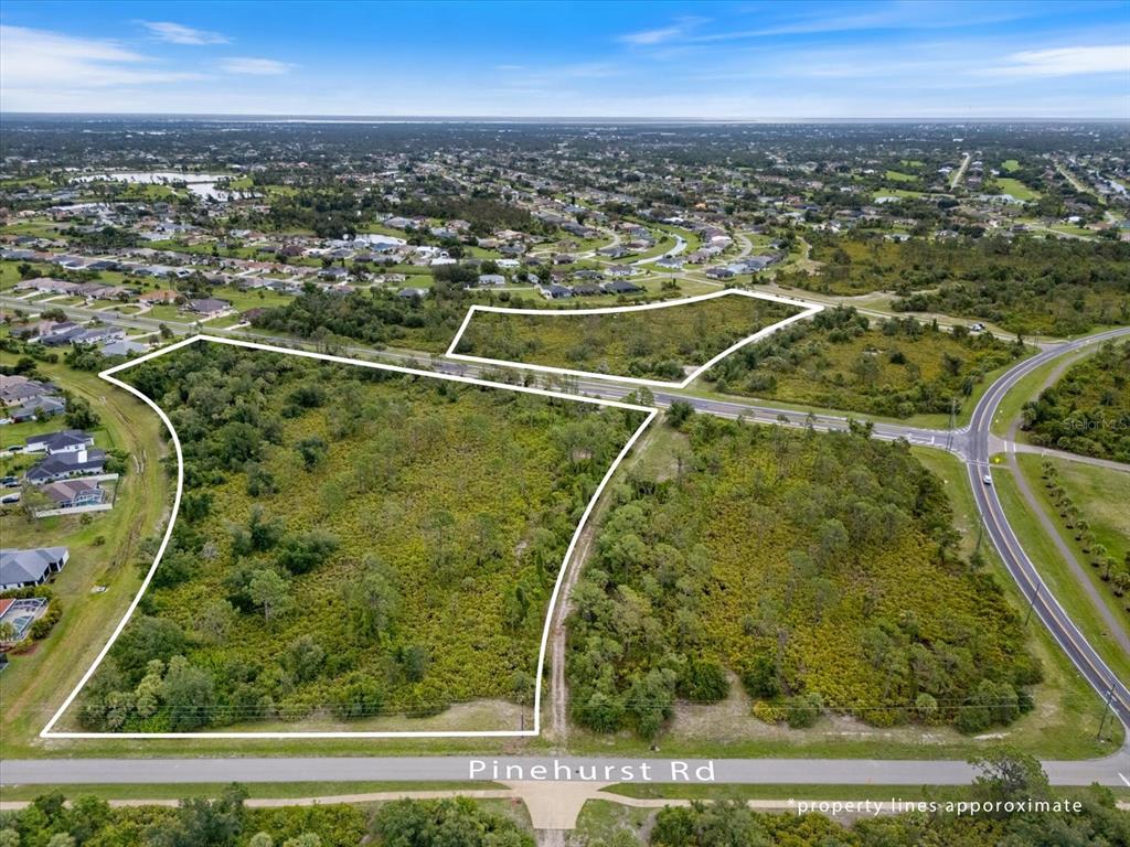 An aerial view shows three undeveloped, wooded land parcels outlined in white along Pinehurst Road — 151 ROTONDA BOULEVARD N, ROTONDA WEST, FL