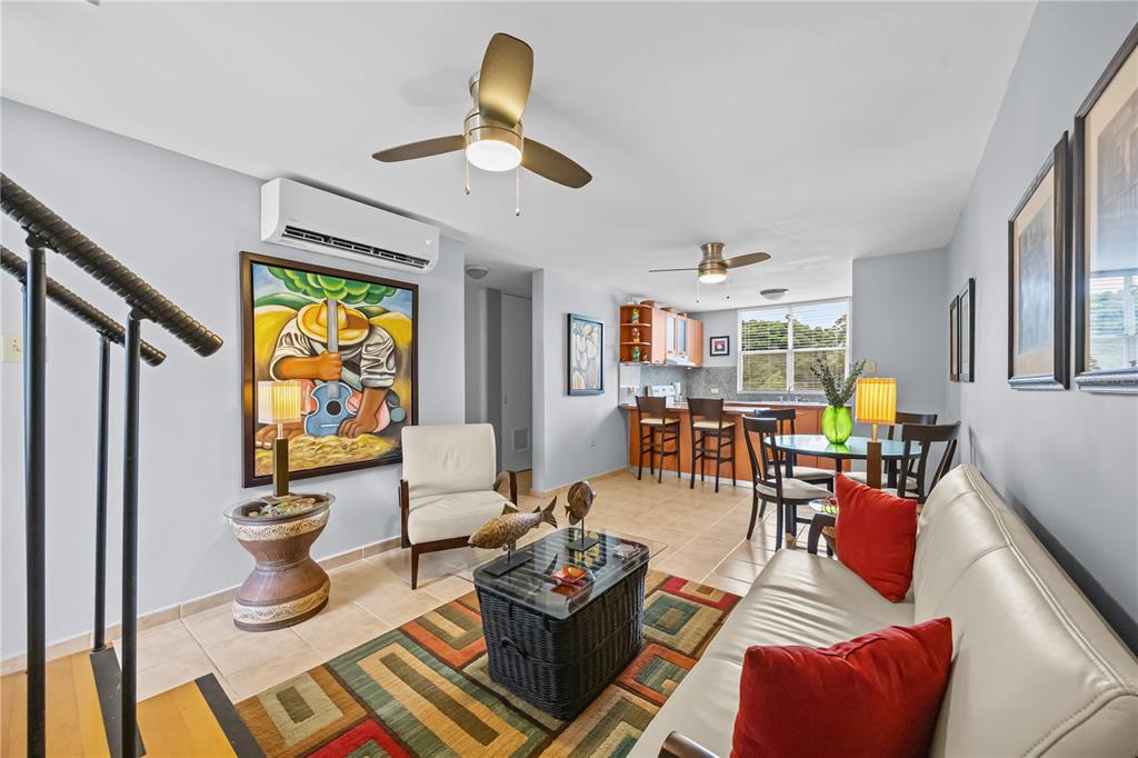 A living room and kitchen area with tile floors, a ceiling fan, and colorful decor — 26 CALLE CAMBIJA UNIT PH B-312, RINCON, PR