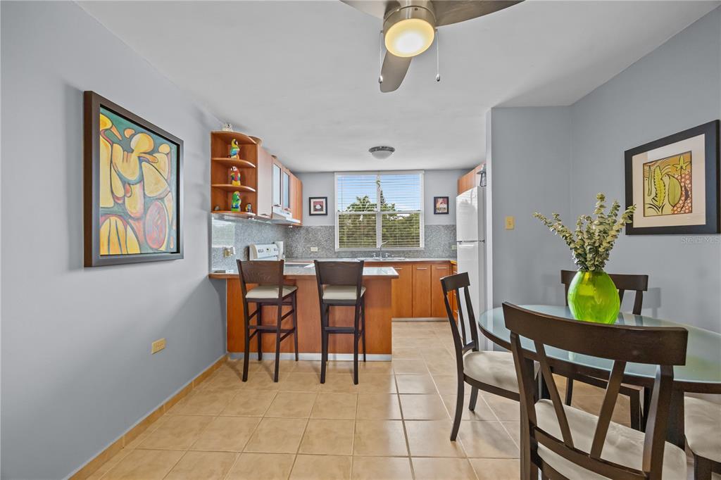A kitchen with wood cabinets, a breakfast bar, and an adjacent dining area with tile — 26 CALLE CAMBIJA UNIT PH B-312, RINCON, PR
