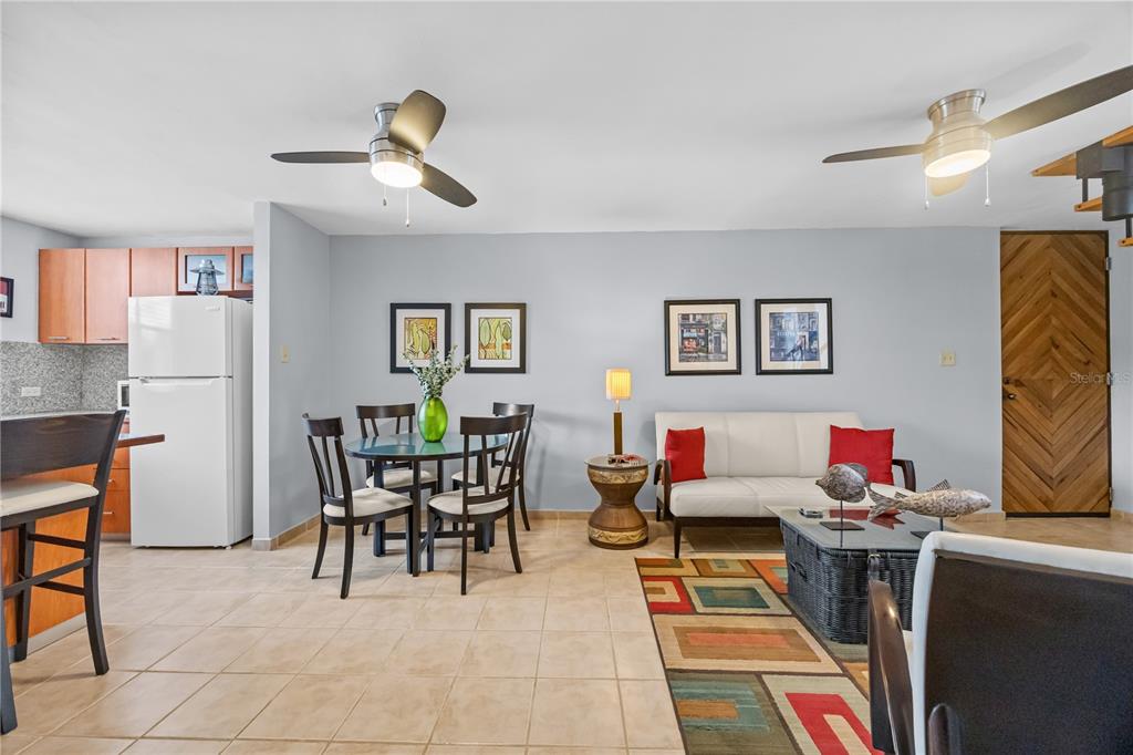 A combined kitchen, dining, and living area features tile flooring, a white sofa, and ceiling fans — 26 CALLE CAMBIJA UNIT PH B-312, RINCON, PR